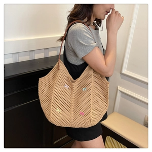 Detail of beige woven tote bag with 3D colorful bows and slim brown leather shoulder strap