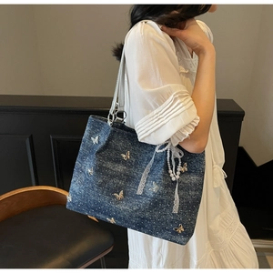 Model wearing a blue denim tote bag with butterfly appliques and white polka dots