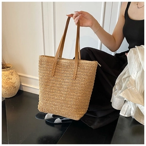 Detail of hand-woven straw tote with smooth brown shoulder strap and secure top zipper