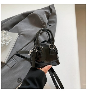 Close-up of black patent leather shell bag with silver hardware and high-gloss finish