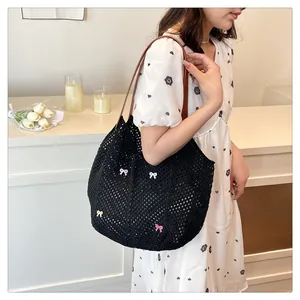 Detail of black crochet tote bag with colorful 3D bow accents and brown leather shoulder strap