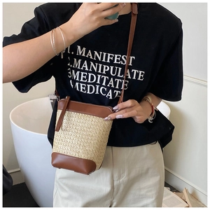Detail der handgewebten Stroh-Eimertasche mit braunem Lederriemen und Randverzierung