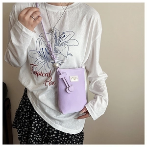 Détail du sac de téléphone lilas avec bandoulière tressée, perles et charms en cœur