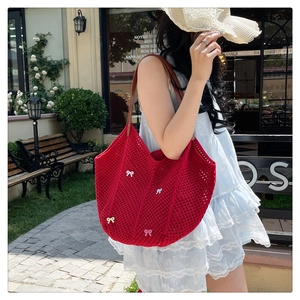 Macro shot of red crochet tote bag featuring 3D bow accents and brown leather straps