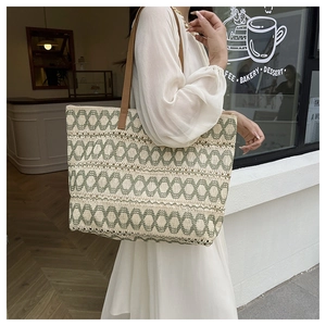 Detail of woven tote bag with green chain pattern and brown leather straps