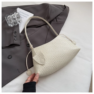 Detailed close-up showing the woven texture and crescent shape of the cream underarm bag