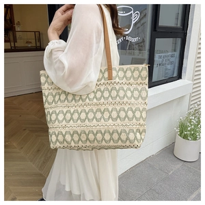 Detail of hand-woven straw tote with geometric patterns and brown leather handles