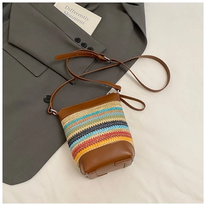Detail der bunten gewebten Stroh-Mini-Eimertasche mit braunem Lederbesatz und Trageriemen