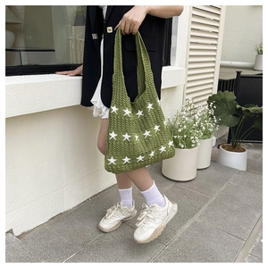 Dettaglio della borsa tote in maglia verde erba con motivo a stelle bianche e trama intrecciata