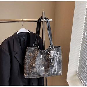 Close-up of denim tote bag with butterfly print and white lace pearl bow charm