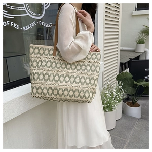 Detailed texture of woven hollow paper straw tote with green geometric patterns