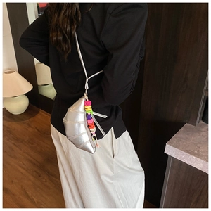 Detail of silver metallic croissant crossbody bag with a colorful letter bead charm accessory