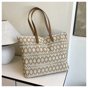 Detail of hollow woven paper straw tote with round patterns and brown leather strap