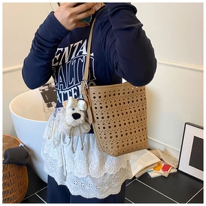 Detail of khaki bucket bag with laser-cut hollow pattern and cute dog pendant
