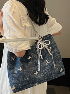 Blue denim tote bag with butterfly appliques and pearl bow charm shown on model