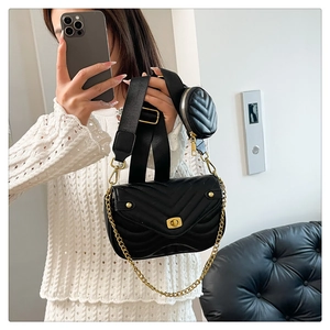 Detail of black quilted crossbody bag with small round pouch and gold hardware
