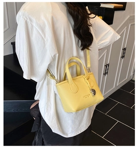 Detail of yellow lychee texture mini crossbody bag with metal sphere charm and handles