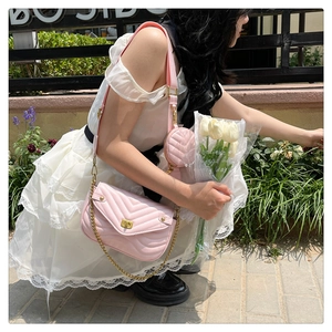 Pink quilted shoulder bag with chain strap and small round coin purse shown on a model outdoors