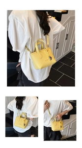 Detail view of yellow lychee pattern leather tote bag with metallic sphere charm and logo