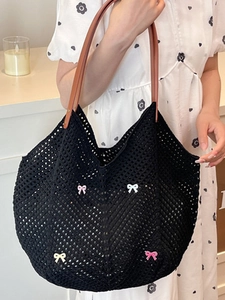 Large black hollow crochet woven tote bag with colorful bows and brown leather straps