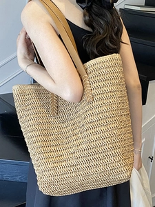 Minimalist woven straw tote bag with brown leather handles for summer beach vacations
