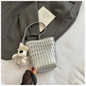 Detail of silver laser-cut cutout bucket bag with a cute white plush bear charm