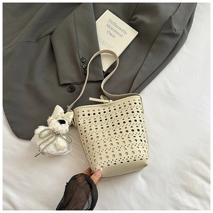 Detail of laser-cut hollow pattern on beige PU leather bucket bag with plush charm