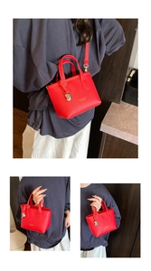 Detail view of red lychee grain leather mini tote bag with gold logo and metal charm