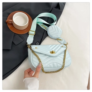 Detail of light blue quilted crossbody bag with golden chain and mini round pouch charm