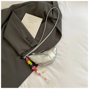 Detail of silver croissant bag with colorful CHOSE beads on a grey blazer backdrop