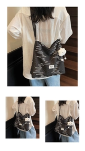 Detail view of black canvas tote bag with white zigzag texture and cloud plush charm