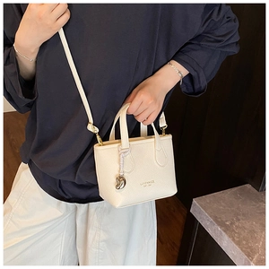 Detail of cream-colored lychee leather mini tote with brand logo and gold hardware