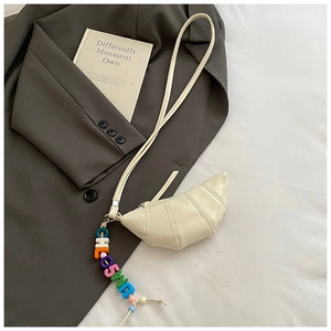 Detail of cream croissant bag featuring textured faux leather and colorful letter bead charm