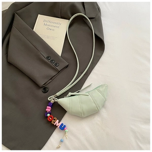 Detail of light green croissant bag featuring unique bead charms and pleated texture