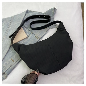 Detail view of the black crescent bag showing nylon texture and leather strap buckle