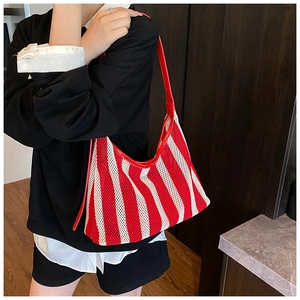 Sac fourre-tout en maille à rayures rouges et blanches porté à l'épaule sur mannequin