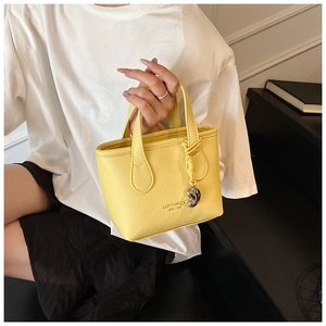 Detail of yellow pebbled leather handbag with silver heart pendant and brand lettering