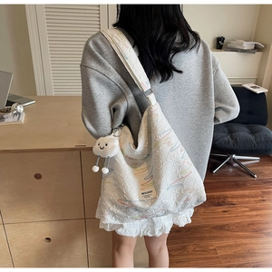 Detailed side view of white canvas hobo bag with colorful embroidery and cloud charm
