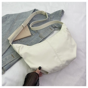 Detail view of cream corduroy hobo bag texture with adjustable strap on white fabric