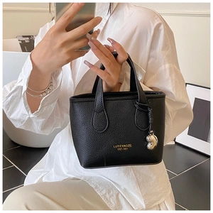 Close-up of black lychee leather handbag with gold logo and silver heart pendant