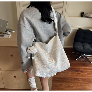 Detailed view of white jacquard tote bag with wave embroidery and plush cloud charm