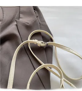 Détail de la bandoulière réglable en cuir blanc cassé avec boucle argentée sur le sac