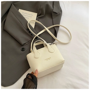 Close-up of cream white leather bucket bag with textured grain and gold logo lettering