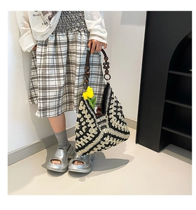 Detail of bohemian black and white crochet tote bag with dark polished wooden bead handle