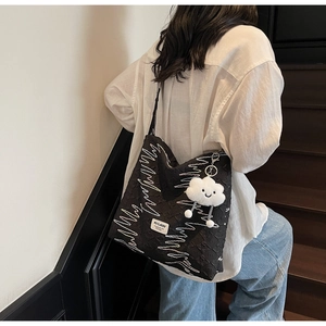 Detail of black canvas tote bag with wave embroidery and plush cloud charm