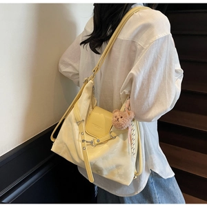 Detailansicht der cremefarbenen Tasche mit Schnallenklappe und Bären-Anhänger