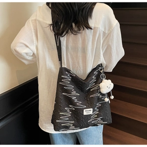 Detail of black textured canvas tote with white zigzag embroidery and cloud charm