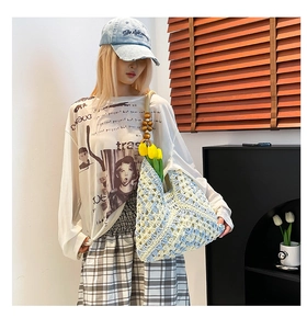Detail of hand-woven tote bag with blue floral patterns and wooden beaded handle