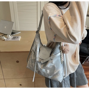 Silberne Metallic-Tragetasche mit Wolkentextur und Bärenanhänger an einem Modell