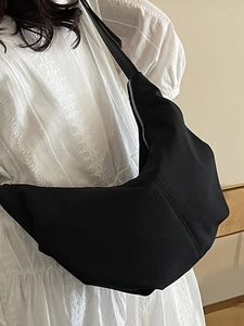 Minimalist black nylon dumpling bag with crossbody strap for stylish women on white dress